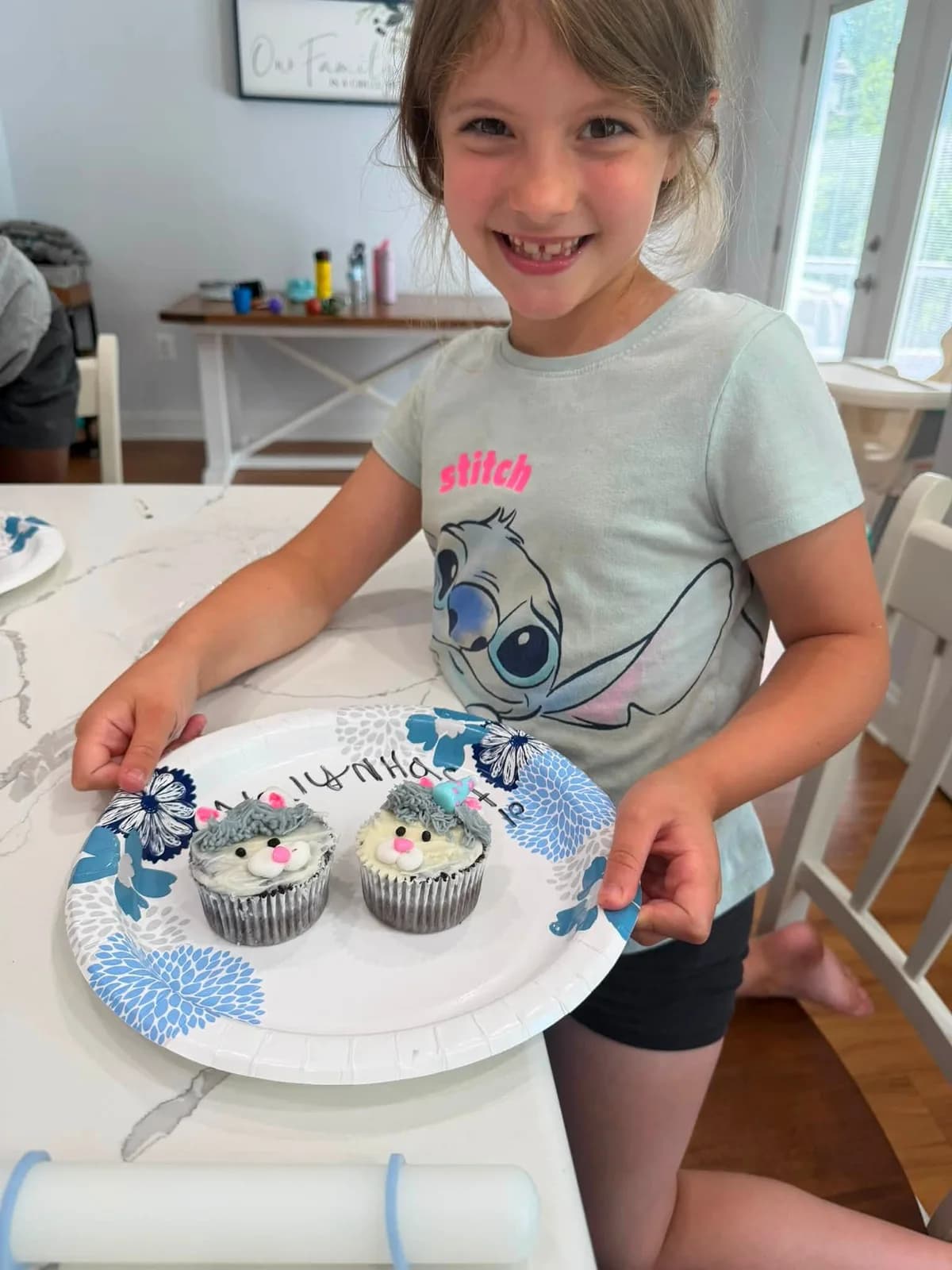 A class participant proudly holding a plate of decorated cupcakes